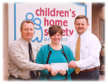 At left, WFEC Manager of Member Services and Communication Terry Mullen and, at right, Gulf Coast Electric Cooperative Manager of Marketing and Member Services Michael White present a $2,500 check to Childrens Home Society of Florida Development Director Wendy F. Davis.
